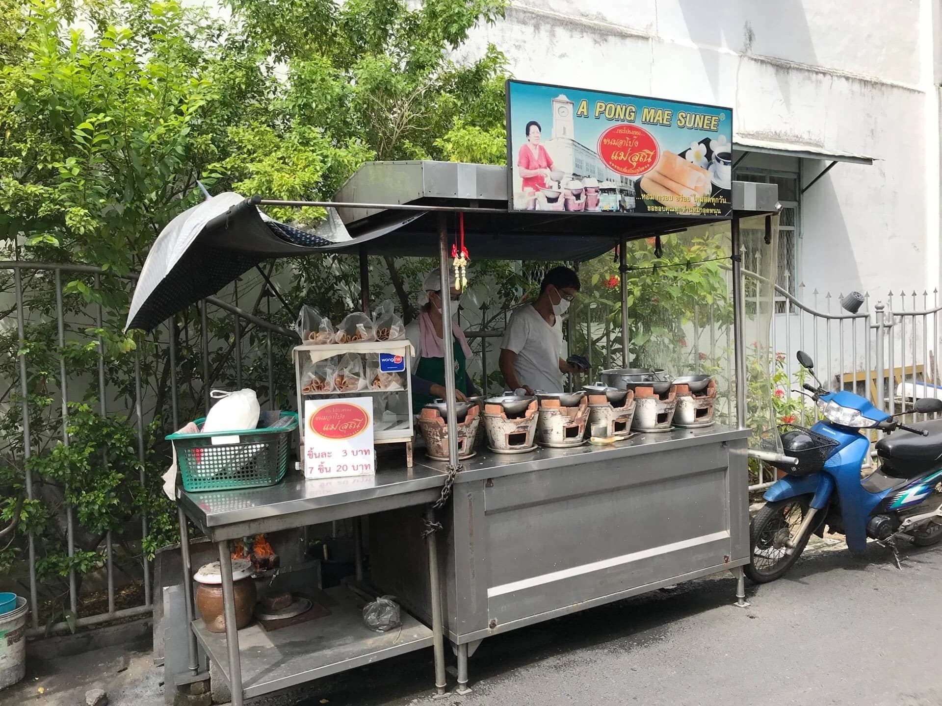 Baking simultaneously across 7 miniature iron woks over glowing mangrove charcoal
